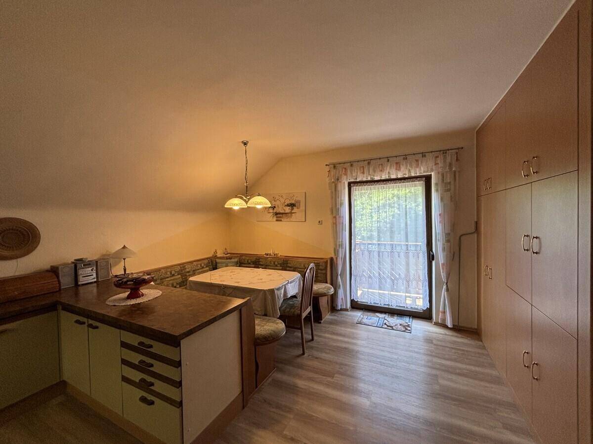Helle Küche mit Dachschräge, Einbauschränken und Essbereich mit Balkonzugang.