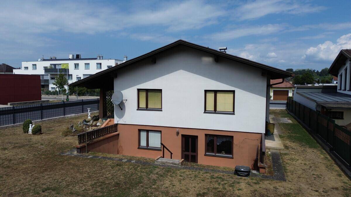 Rückansicht des Einfamilienhauses mit Garten, Terrasse und Zugang zum Untergeschoss.