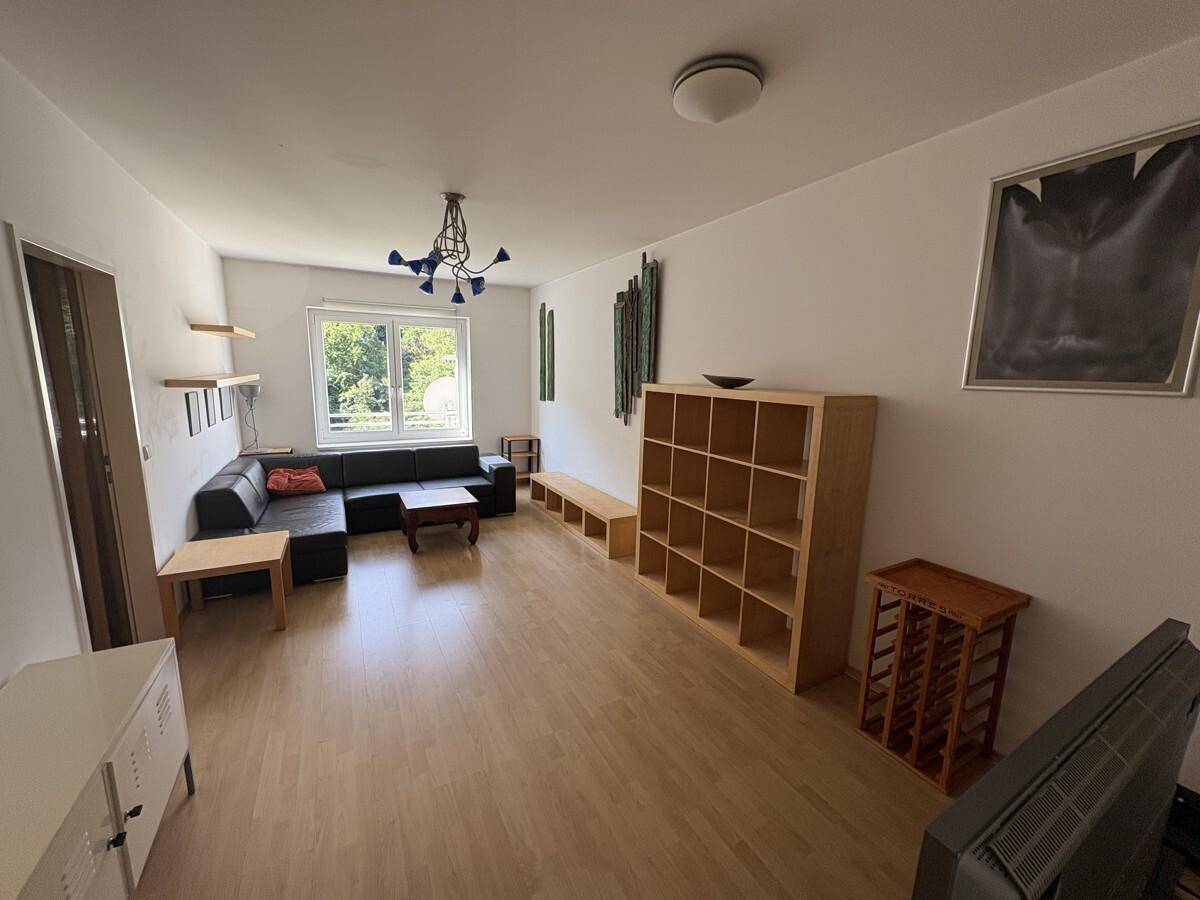 Heller Wohnbereich mit Sofa, Holzregalen und Laminatboden, bietet viel Platz zum Entspannen.