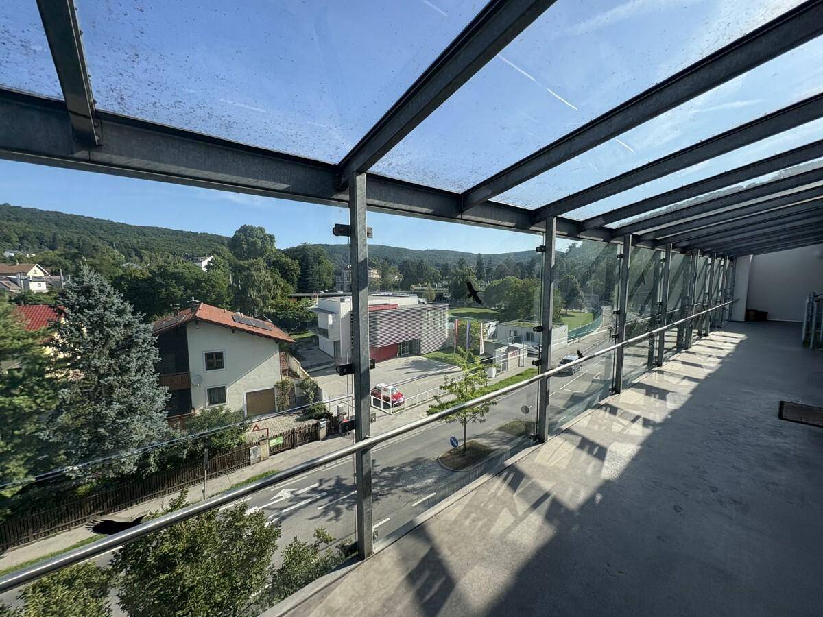 Überdachter Balkon mit Glasgeländer bietet weiten Blick auf die Umgebung und die Straße.