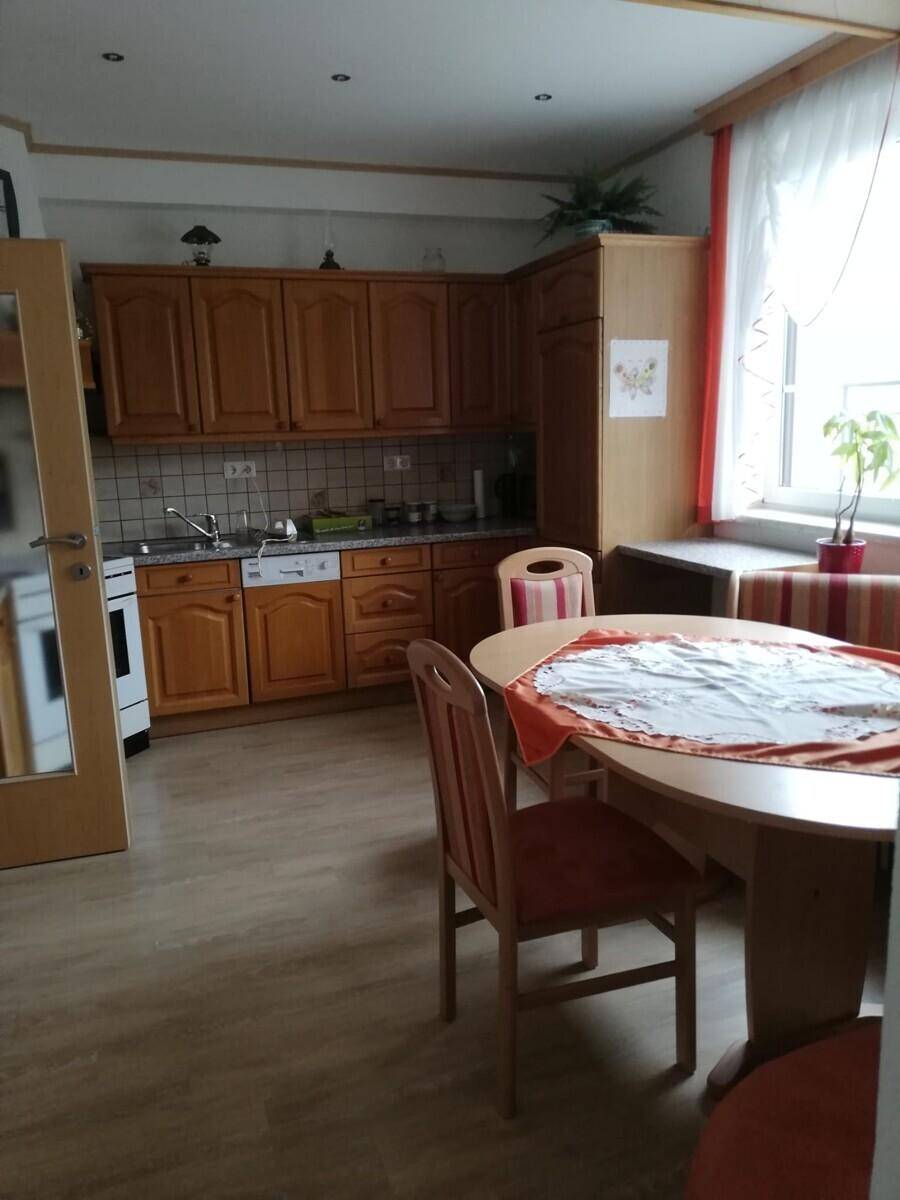 Traditionelle Wohnküche mit Holzeinbauten, Essbereich und Fenster für Tageslicht.