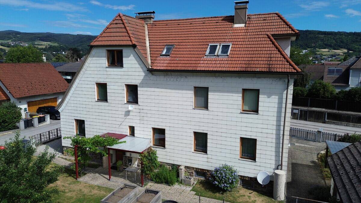 Das Haus von oben mit Garten, überdachter Terrasse und weitem Blick auf die grüne Landschaft.