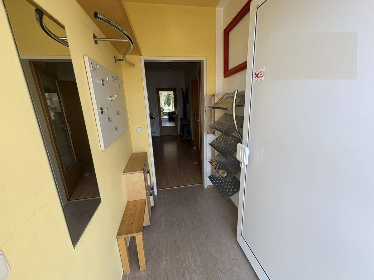 Eingangsbereich mit gelben Wänden, Spiegel und Garderobe, funktional eingerichtet.