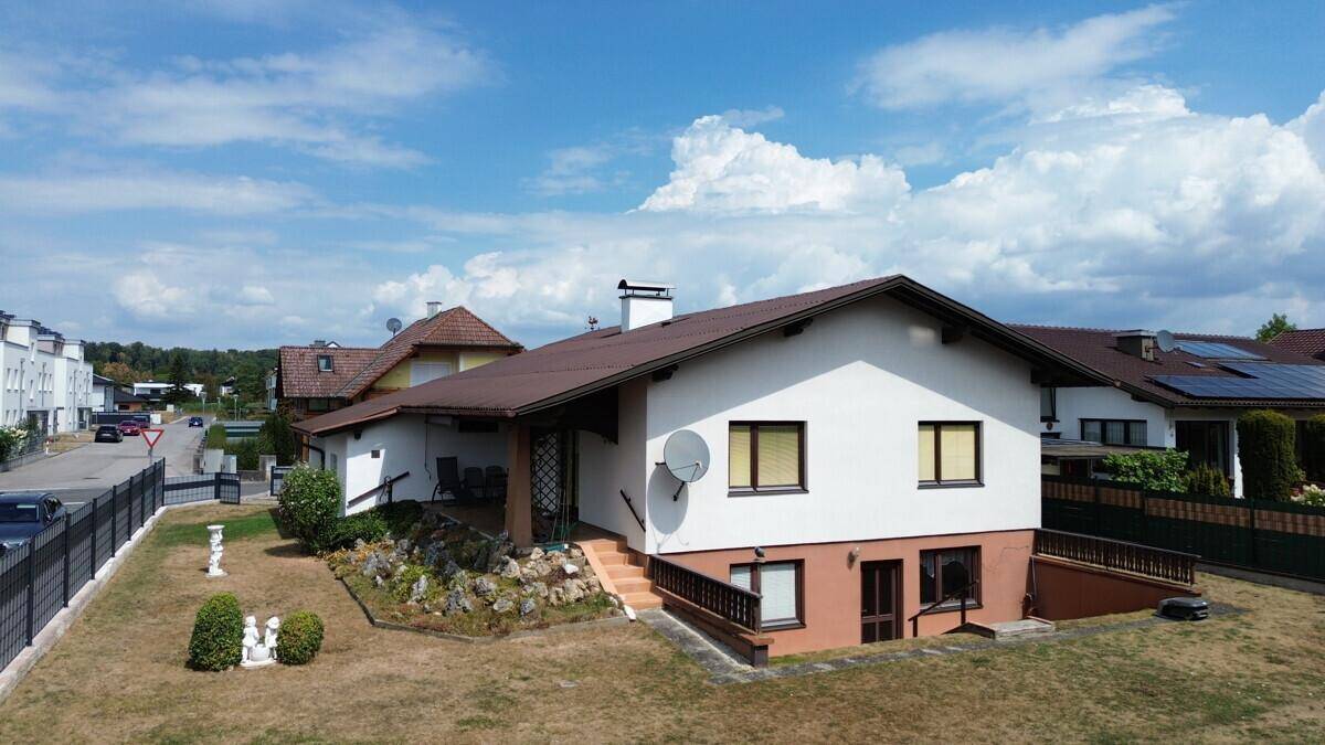 Seitliche Ansicht des Hauses mit überdachter Terrasse und Zugang zum Untergeschoss.