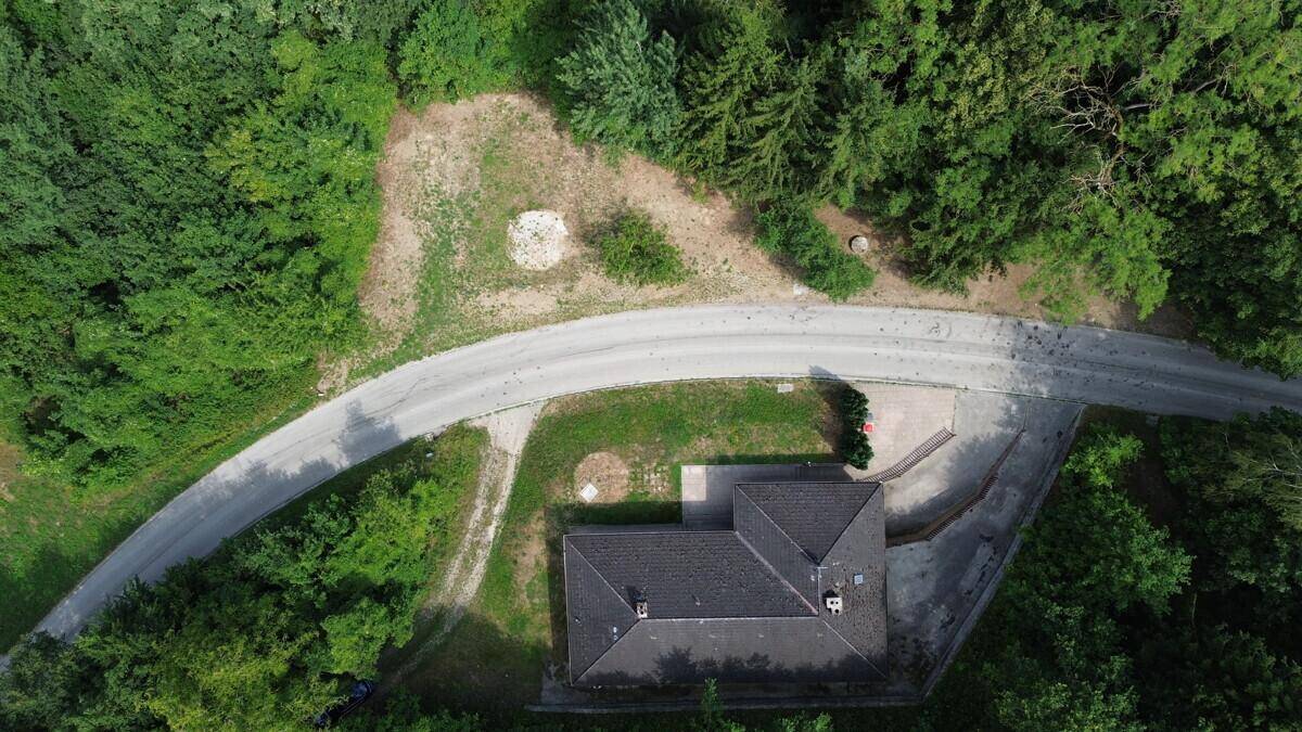 Draufsicht auf das Haus und das Grundstück, eingebettet in eine bewaldete Landschaft.