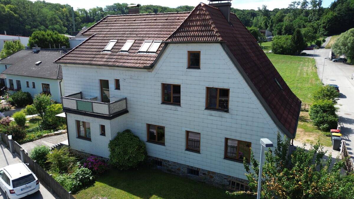 Das Haus von oben mit Balkon, grünem Garten und Blick auf die umliegende Natur.