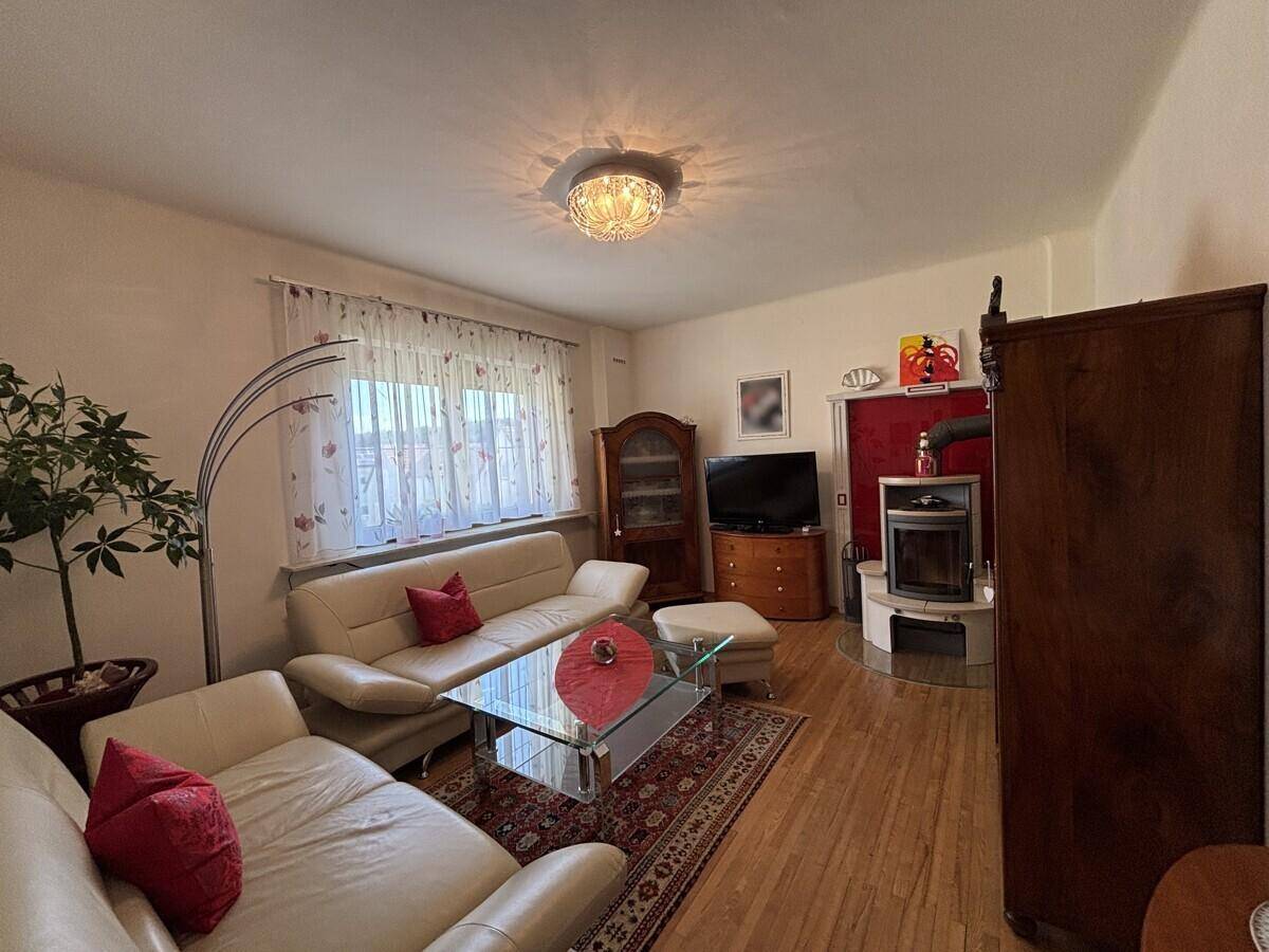 Wohnzimmer mit hellem Ledersofa, Holzboden und modernem Kaminofen.