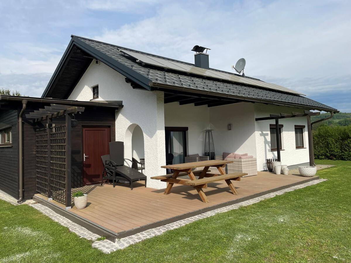 Geräumige Holzterrasse mit Picknicktisch und Lounge-Möbeln, ideal für entspannte Stunden.