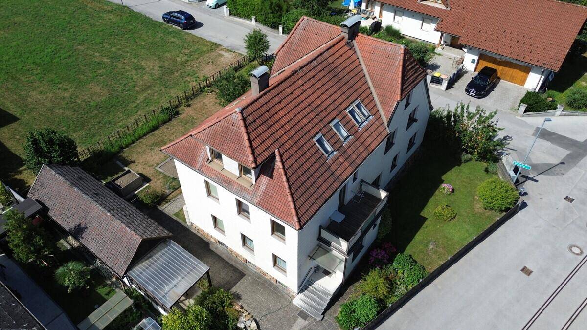 Vogelperspektive des Hauses mit Balkon, Garten und angrenzender Straße in ländlicher Umgebung.