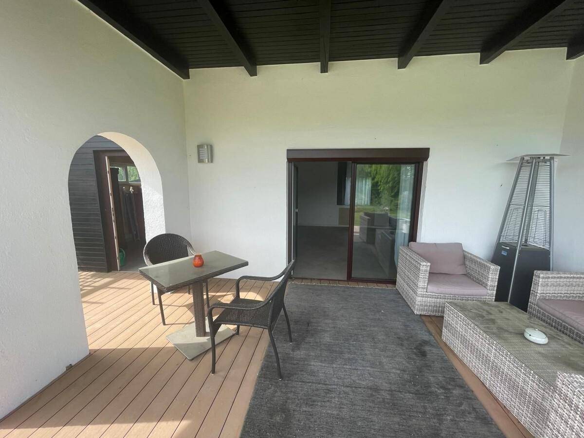 Überdachte Terrasse mit bequemen Lounge-Möbeln und Esstisch, ideal für Mahlzeiten im Freien.