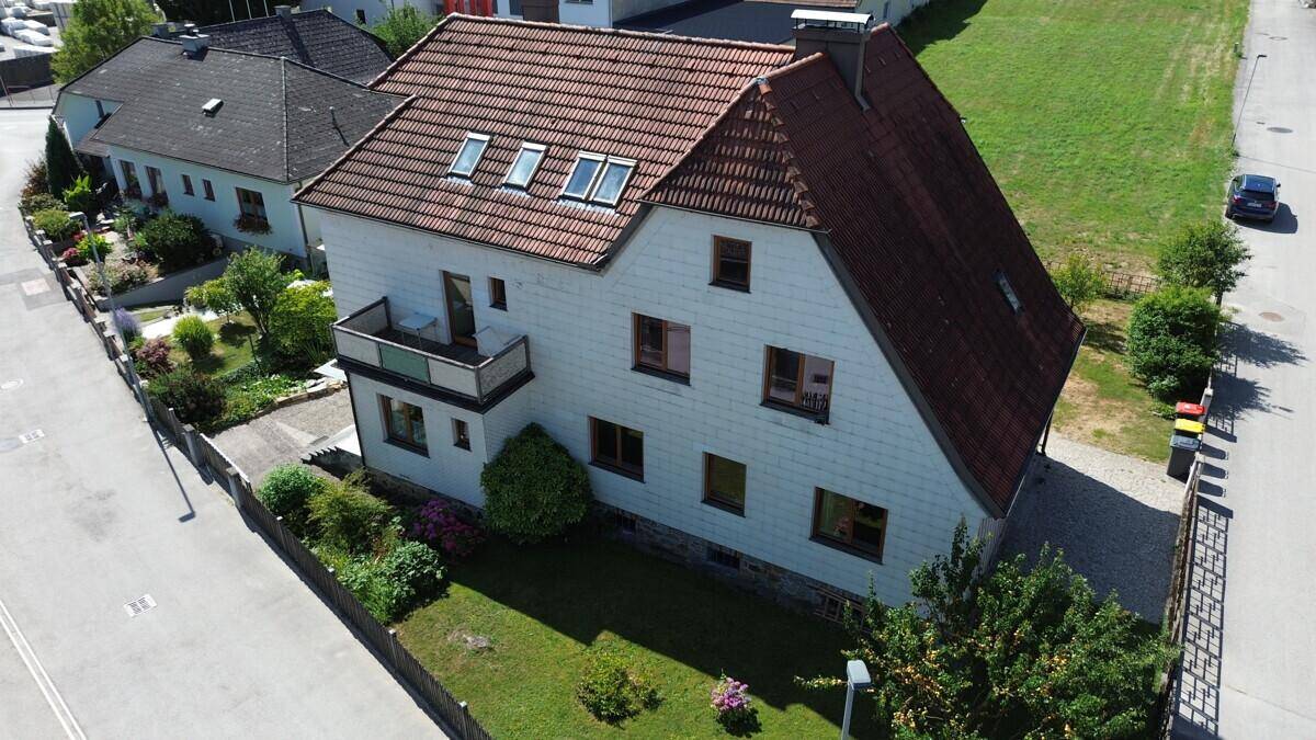 Ansicht des Hauses von oben mit Balkon, gepflegtem Rasen und angrenzender Straße.