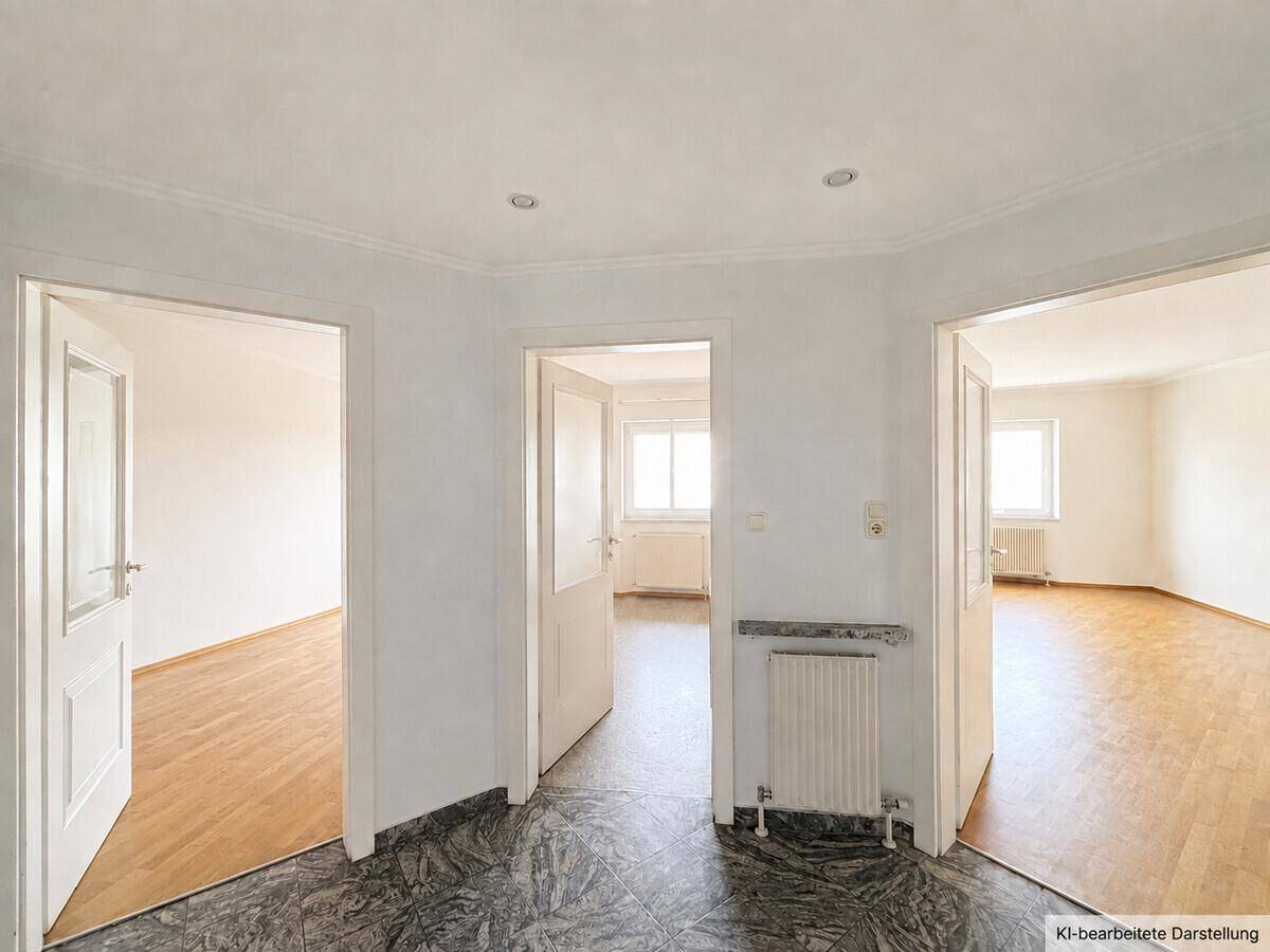 Heller Flur mit dunklem Fliesenboden und mehreren offenen Türen zu angrenzenden Räumen.