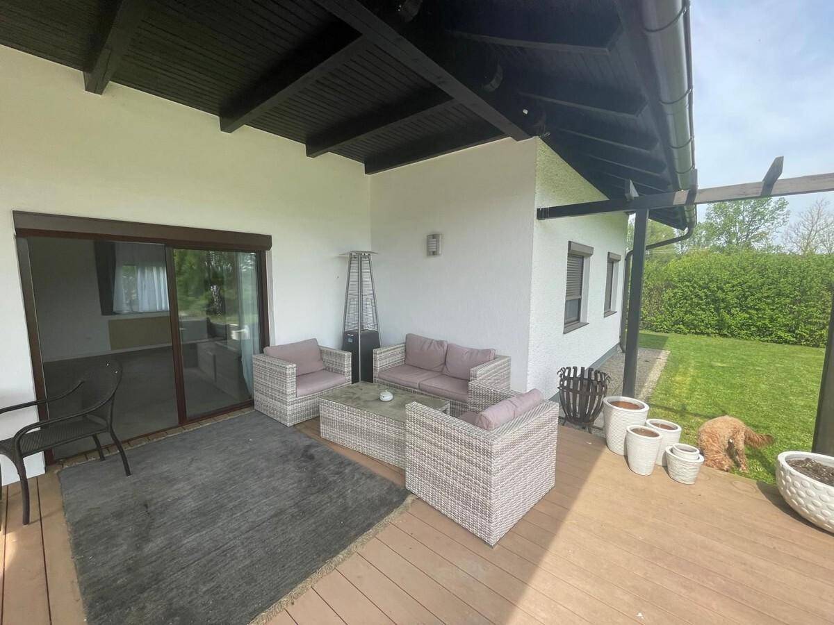 Geräumige überdachte Terrasse mit Lounge-Sitzgruppe und Blick auf den gepflegten Garten.