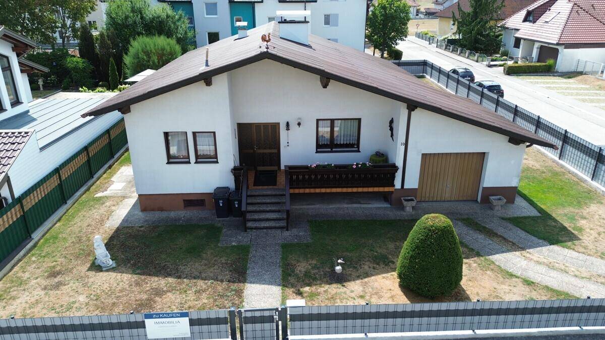 Vorderansicht des Hauses mit gepflegtem Vorgarten und Zufahrt zur integrierten Garage.