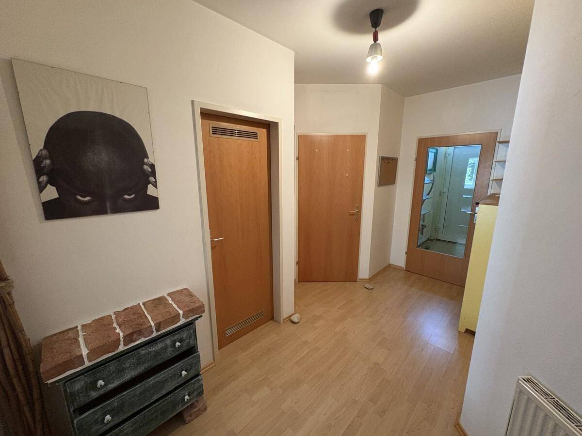 Flur mit Laminatboden und weißen Wänden, dekoriert mit einem modernen Kunstwerk.