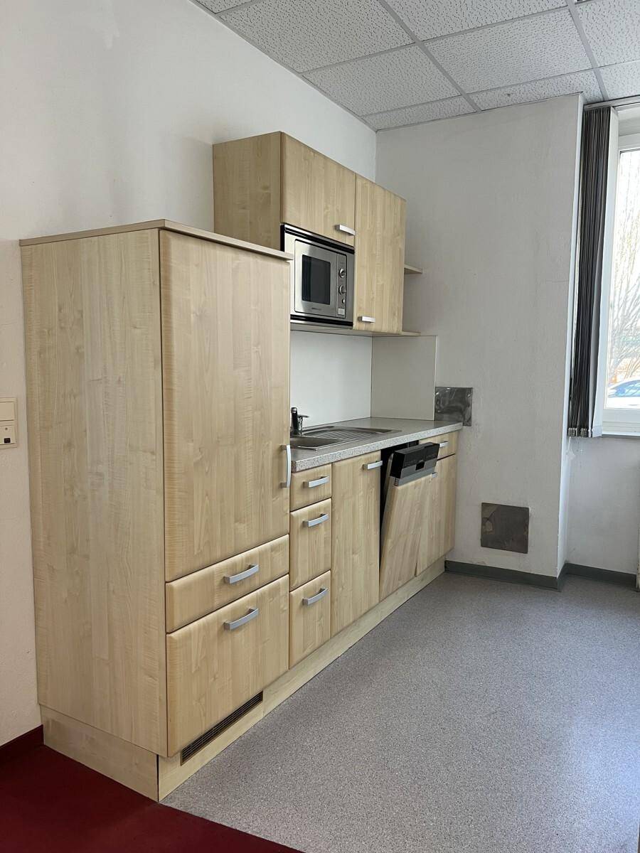Funktionale Küchenzeile mit hellen Holzfronten, integrierter Mikrowelle und Spülmaschine.