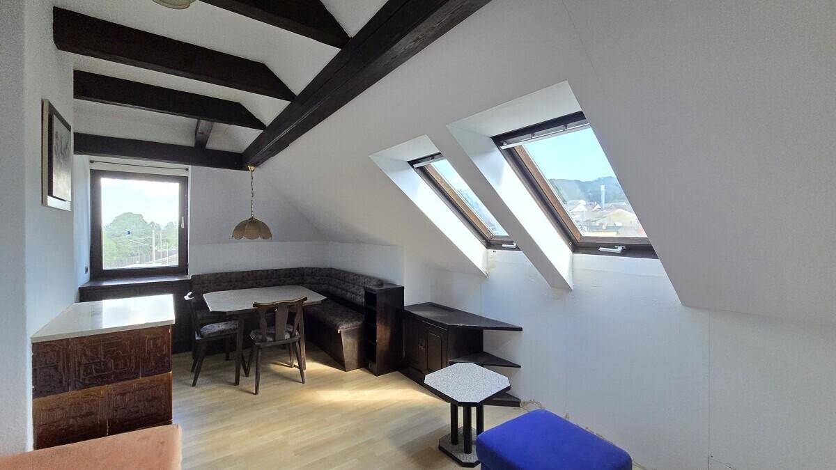 Dachgeschoss-Wohnbereich mit Essnische, Holzbalken und viel Tageslicht durch große Dachfenster.