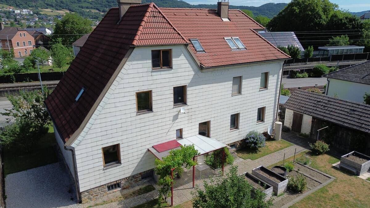 Luftaufnahme des Hauses mit Garten, überdachtem Sitzplatz und Blick auf die ländliche Umgebung.