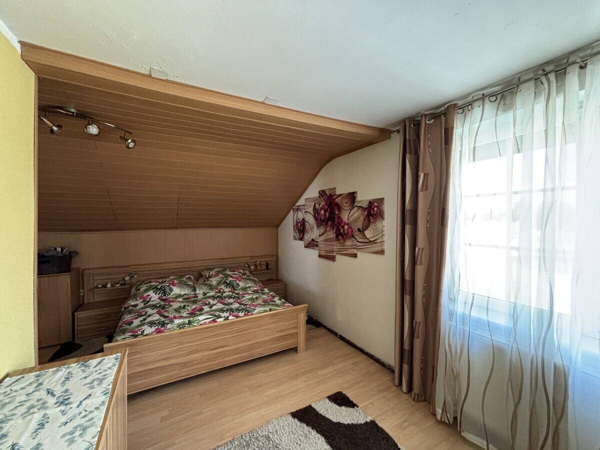 Gemütliches Schlafzimmer mit Holzbett, Dachschräge und Blick ins Grüne.