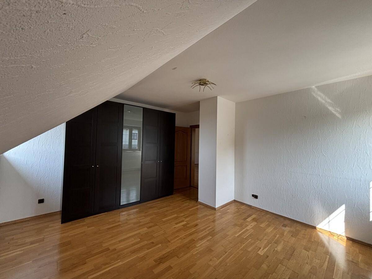 Schlafzimmer mit Holzparkett, großem Einbauschrank und Dachschräge.