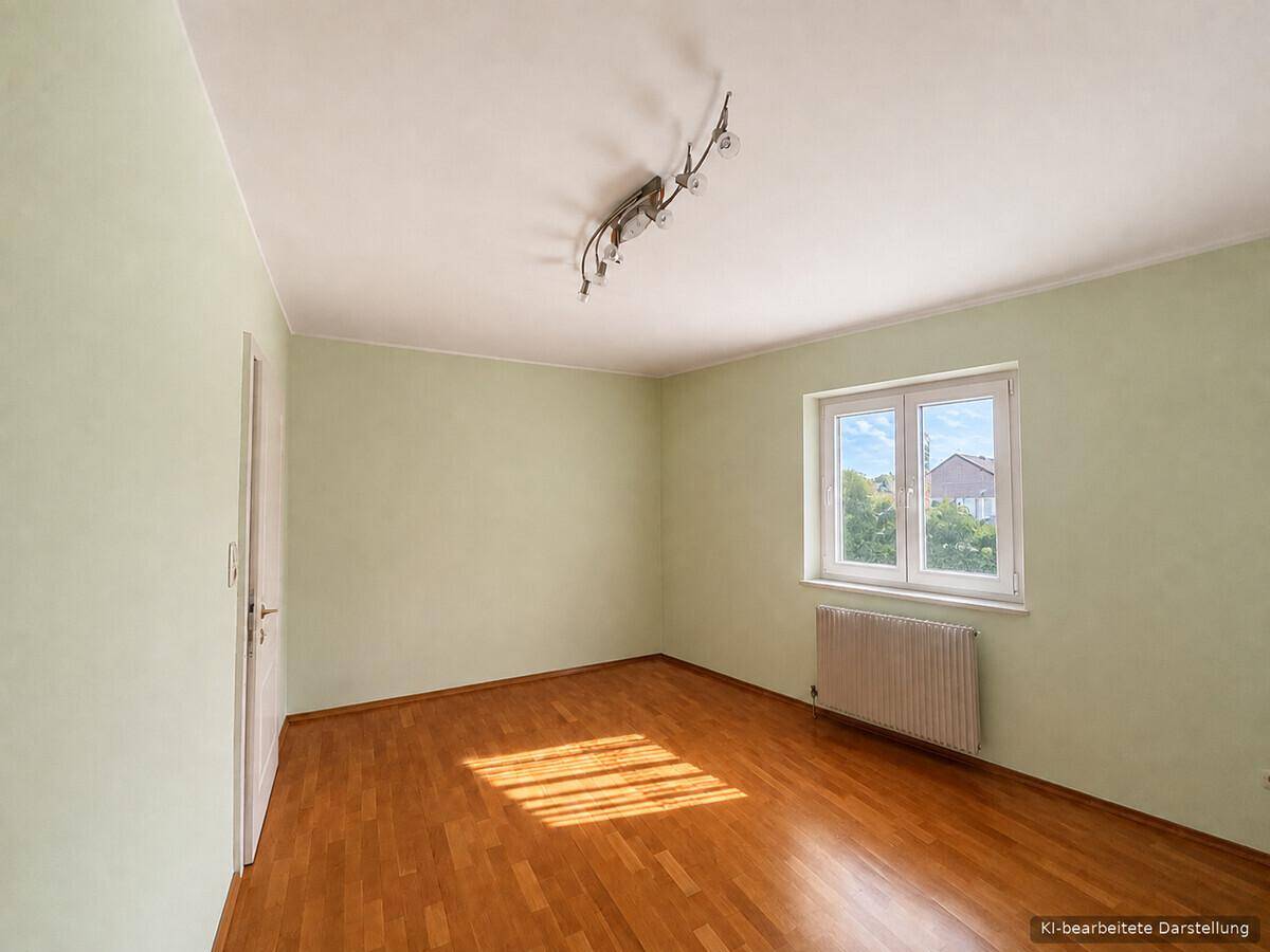Helles Zimmer mit Parkettboden, grünen Wänden und viel Tageslicht durch das Fenster.