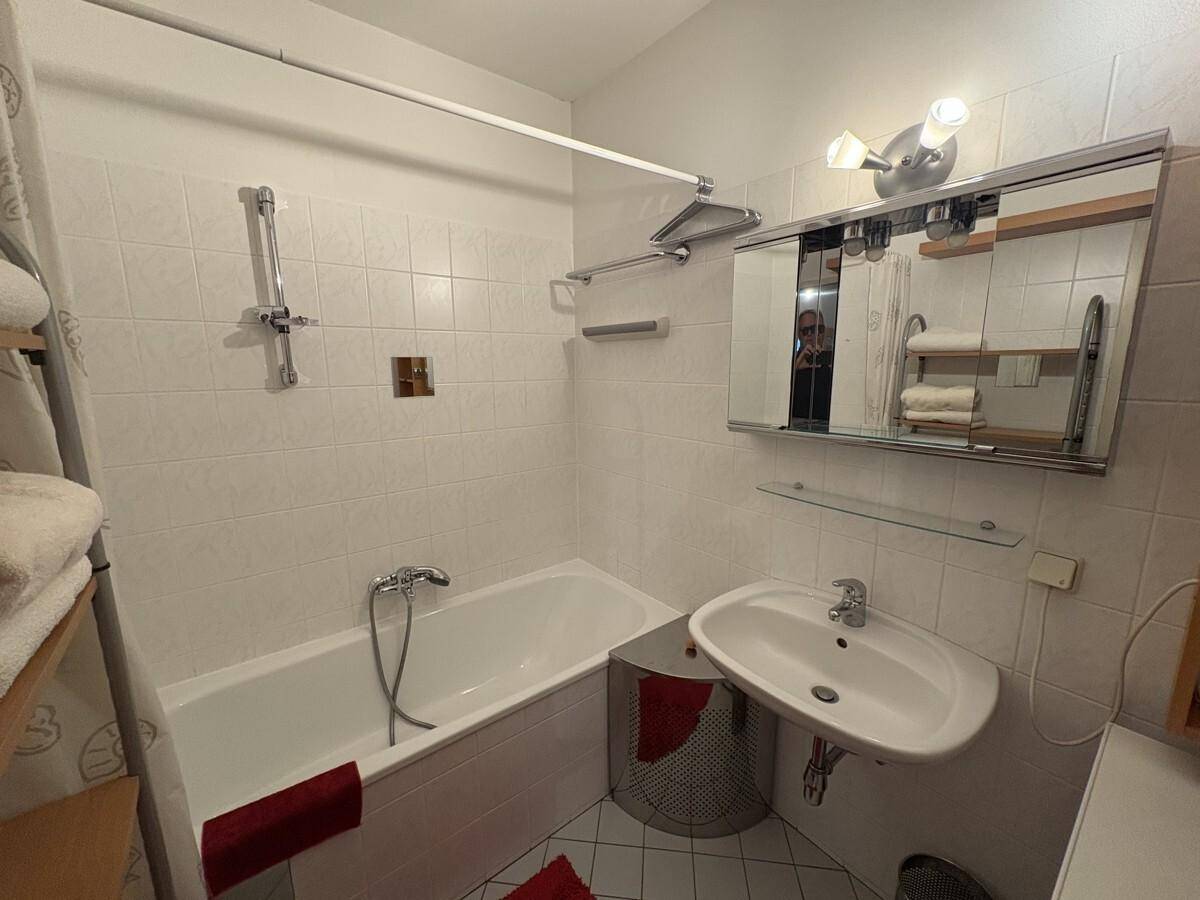 Gefliestes Badezimmer mit Badewanne, Duschfunktion und Waschbecken, funktional ausgestattet.
