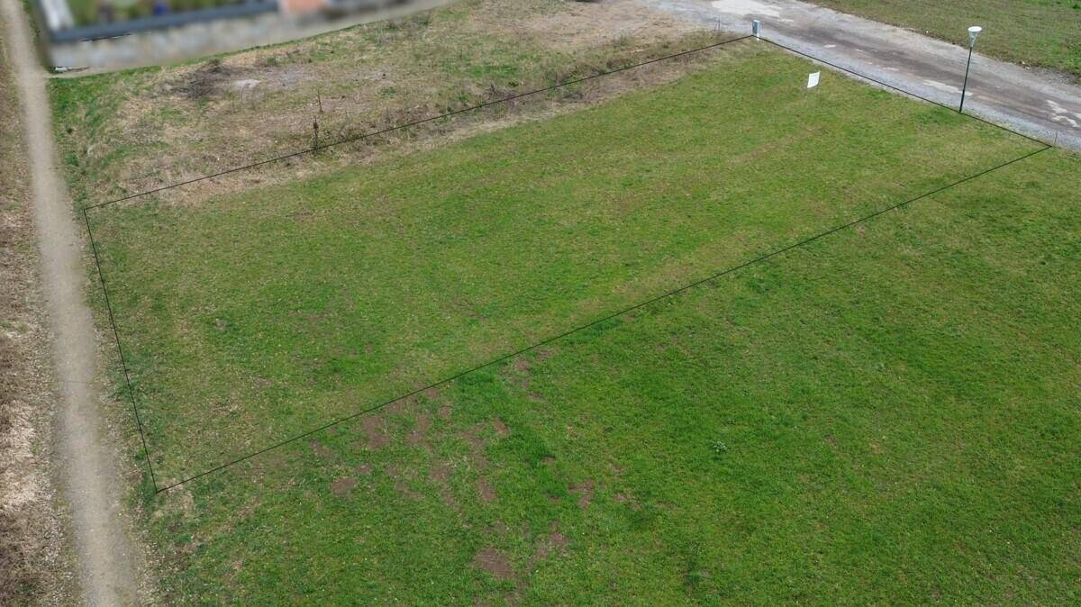 Luftaufnahme eines grünen Grundstücks mit angedeuteten Grenzen und angrenzenden Wegen.