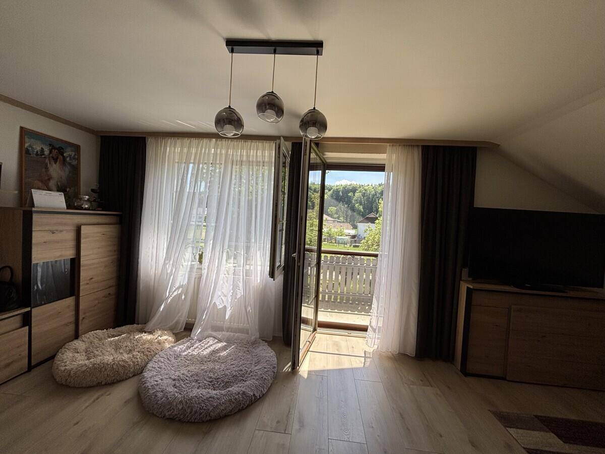Gemütliches Wohnzimmer mit Holzboden, Balkonzugang und viel Tageslicht.