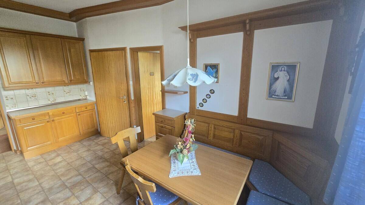 Traditionelle Holzküche mit Essbereich, Fliesenboden und rustikalen Holzelementen.
