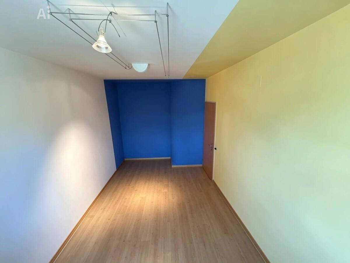 Zimmer mit farbigen Akzentwänden in Blau und Gelb, ausgestattet mit Laminatboden.