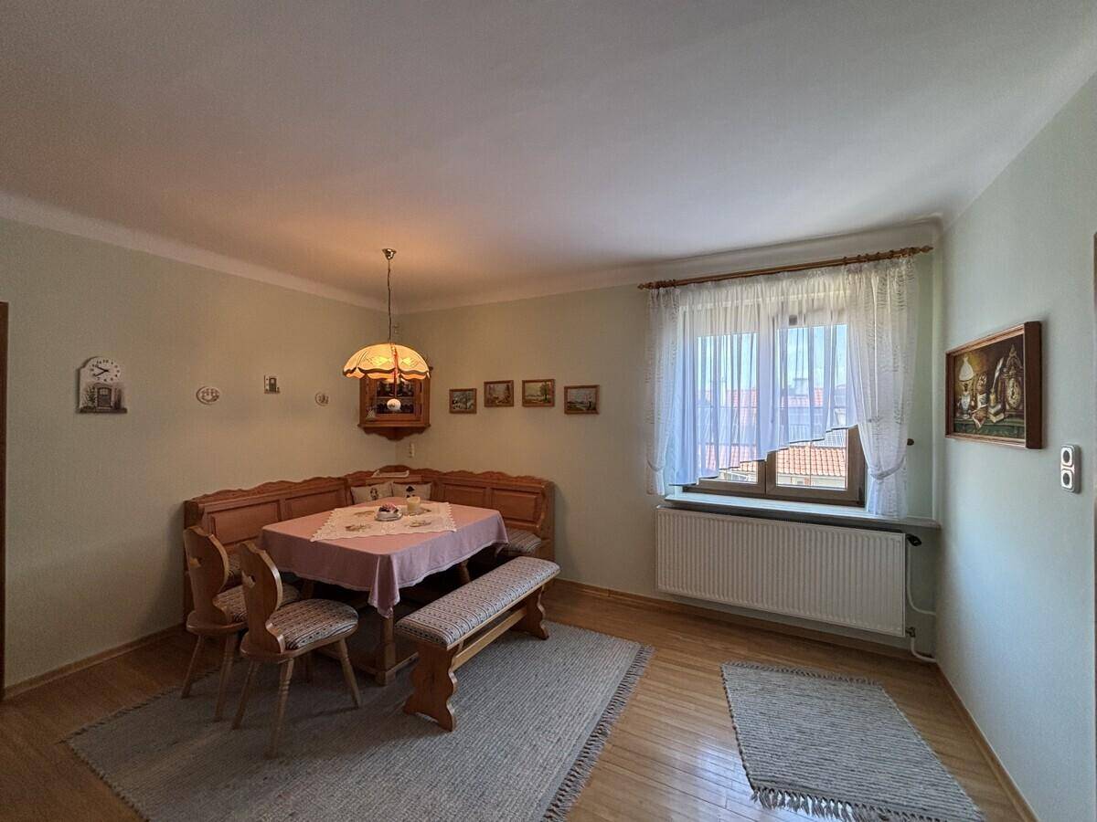 Traditioneller Essbereich mit Eckbank, Holztisch und Blick durch das Fenster.