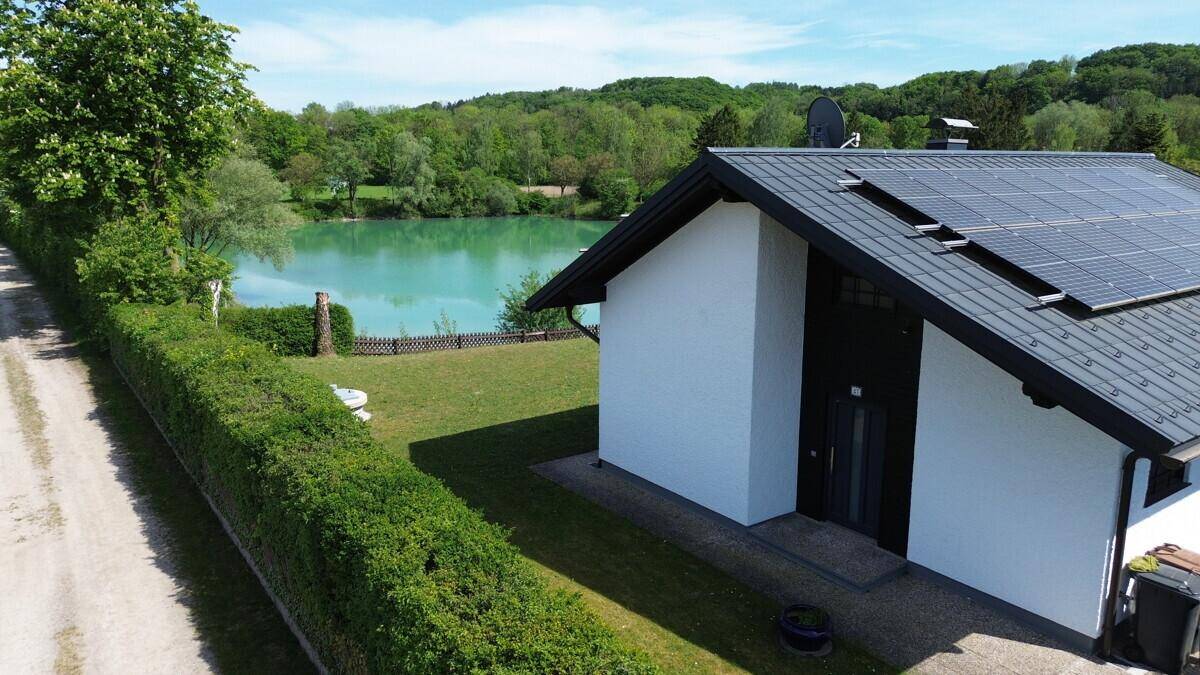 Eingangsbereich des Hauses mit weißer Fassade und Blick auf den angrenzenden See.