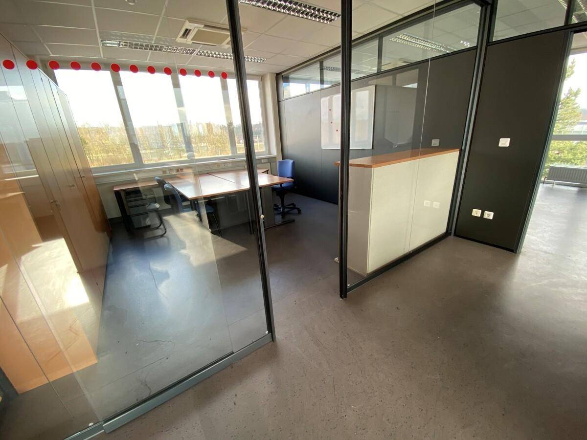 Heller Bürobereich mit Glasabtrennungen, Schreibtischen und Blick auf die Umgebung, ideal für konzentriertes Arbeiten.