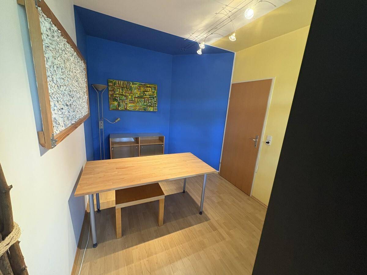 Arbeitszimmer mit farbigen Wänden und Holztisch, ideal für Home-Office oder Hobby.