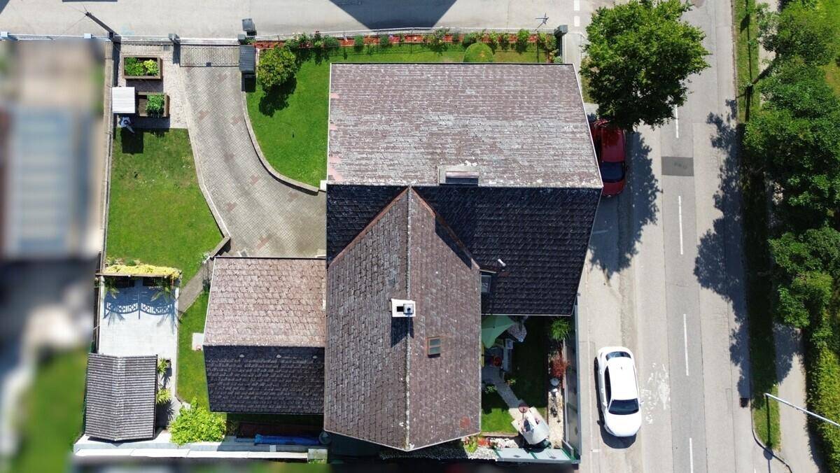 Vogelperspektive eines Einfamilienhauses mit Satteldach, Garten und Zufahrt.
