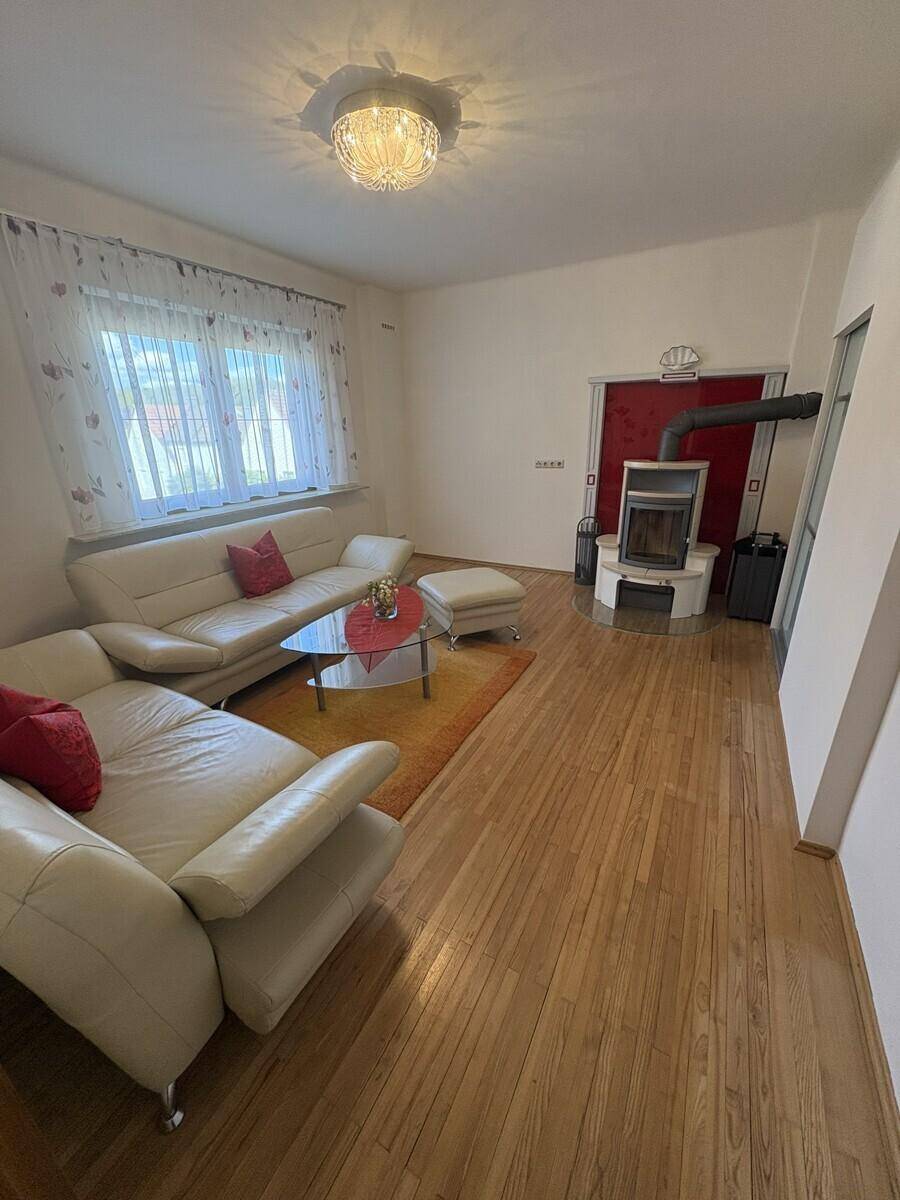 Heller Wohnraum mit bequemen Sofas, Holzofen und großen Fenstern.