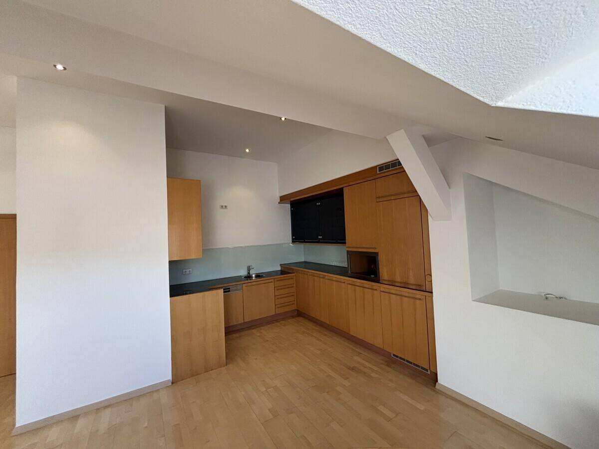 Integrierte Küchenzeile im Dachgeschoss mit Holzfronten, Spüle und Kochbereich, offen zum Wohnraum.