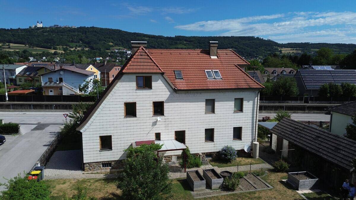 Luftaufnahme des Hauses mit Garten, überdachter Terrasse und weitem Blick auf die Hügellandschaft.