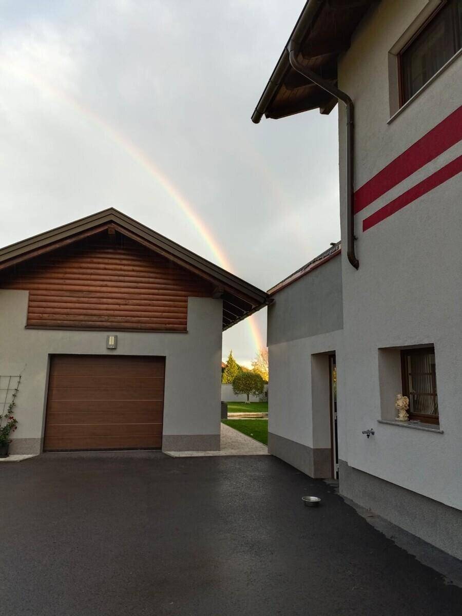 Außenansicht des Hauses mit Garage und einem Regenbogen am Himmel.