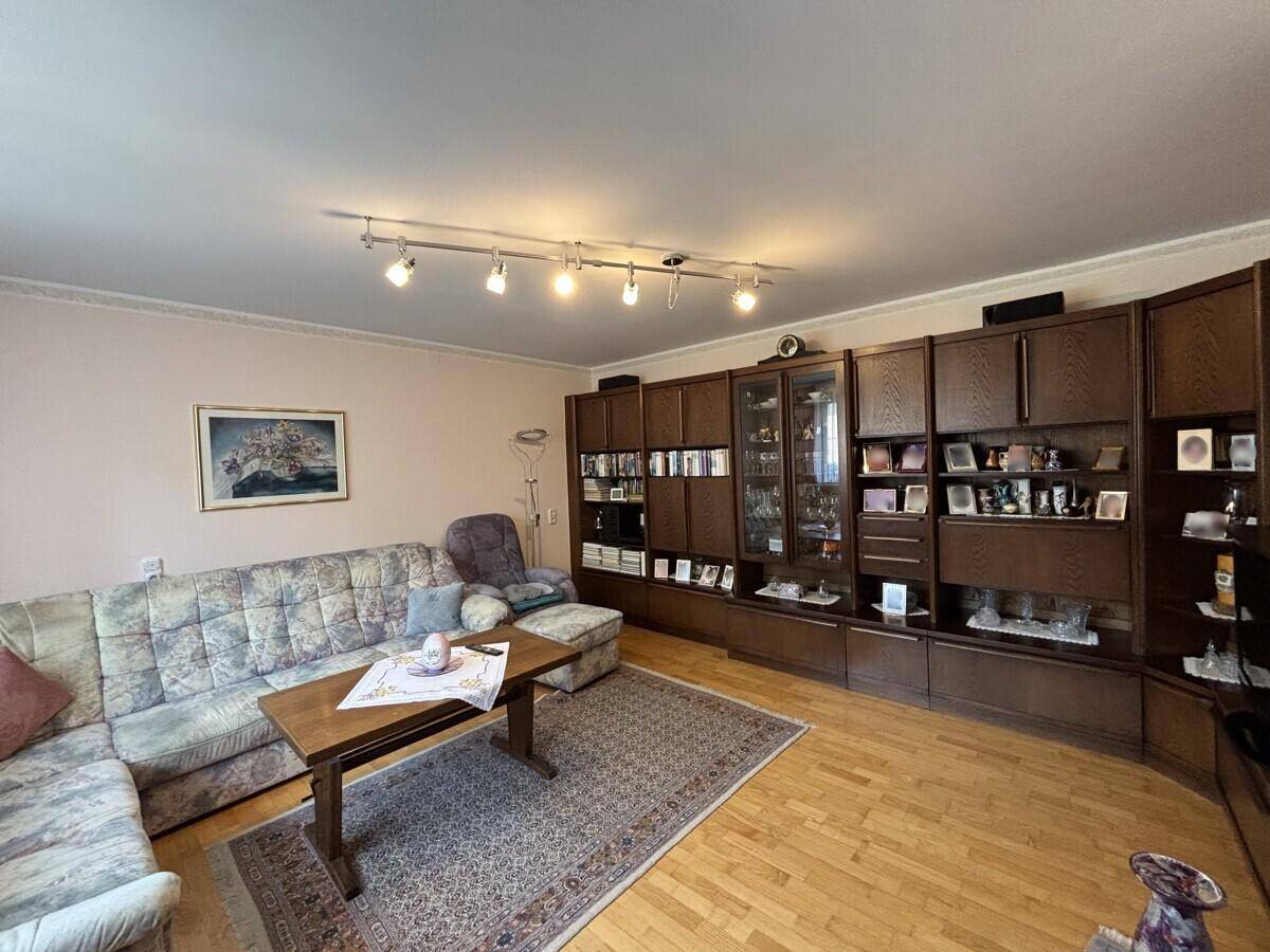 Geräumiges Wohnzimmer mit großem Sofa, Schrankwand und Holzboden.