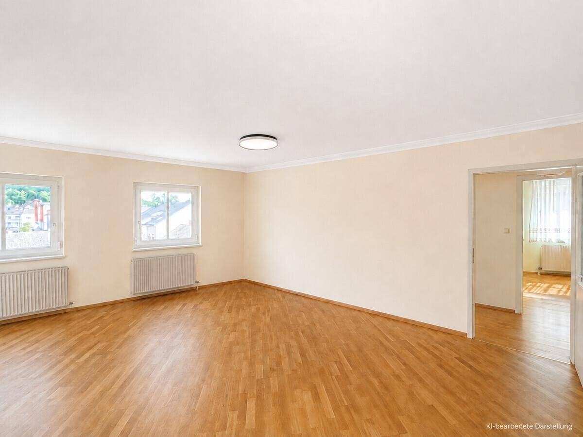 Geräumiges Zimmer mit Holzparkett, hellen Wänden und zwei Fenstern, die viel Licht hereinlassen.