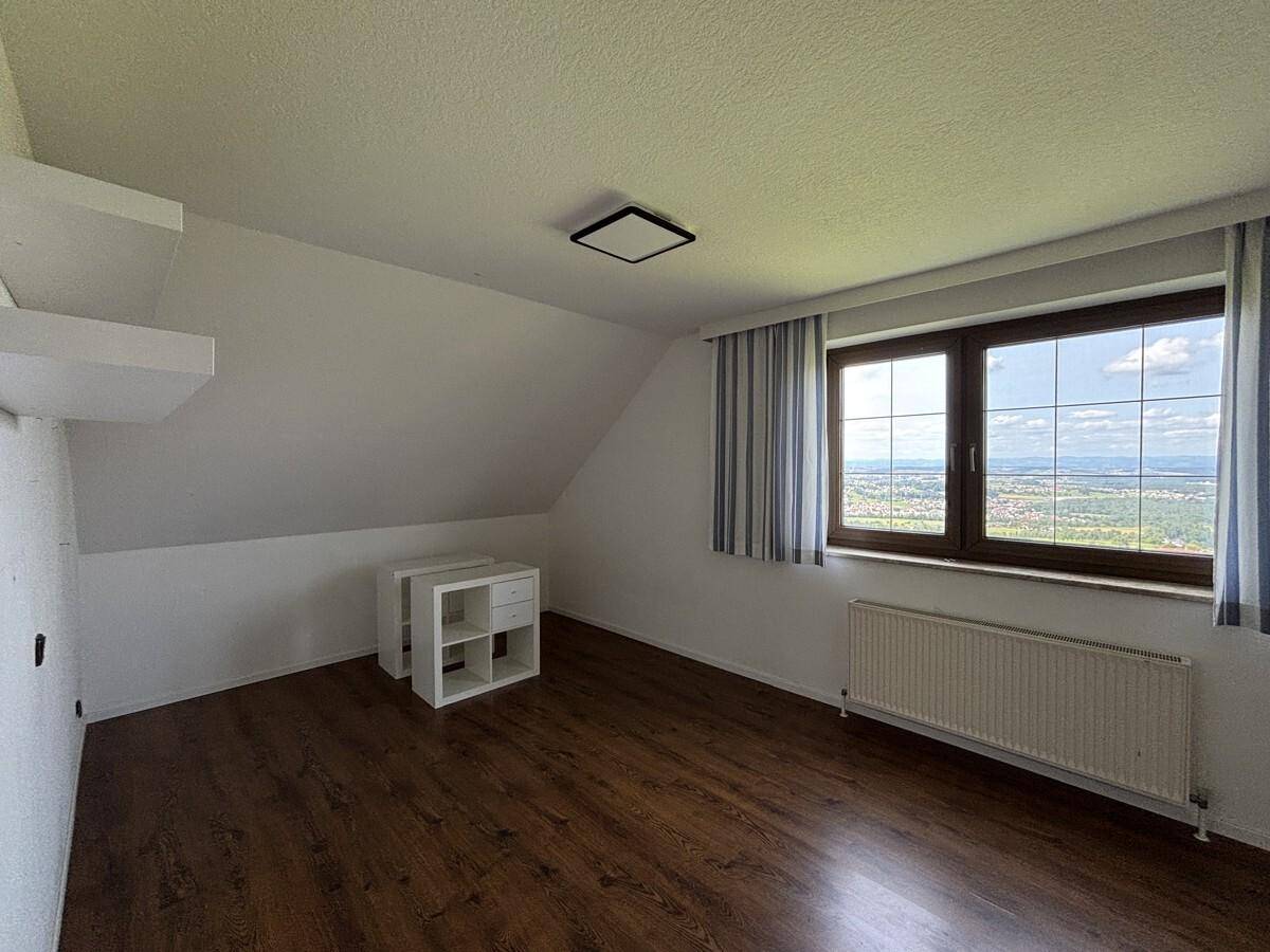 Schlafzimmer mit Dachschräge, Laminatboden und großem Fenster mit weitem Ausblick.