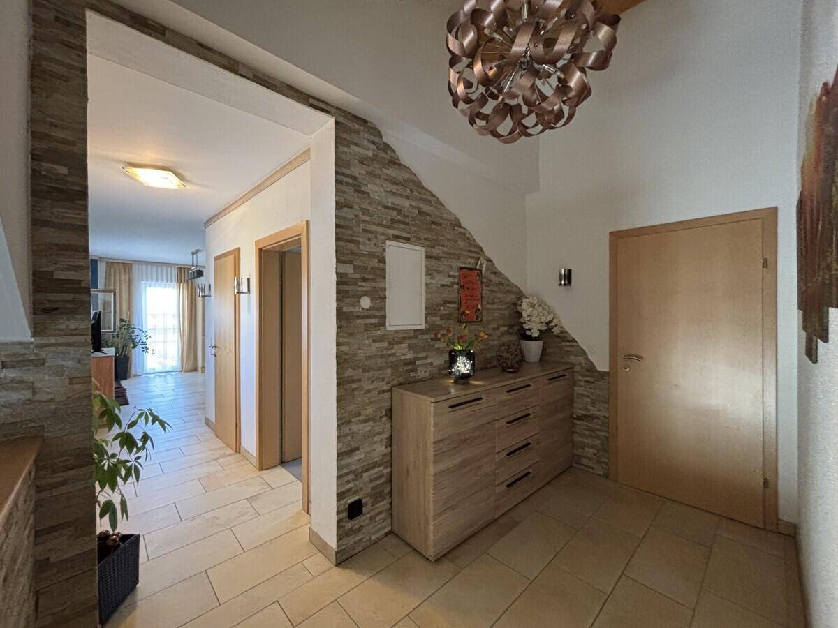 Eingangsbereich mit Fliesenboden, dekorativer Steinwand und modernem Deckenlicht.