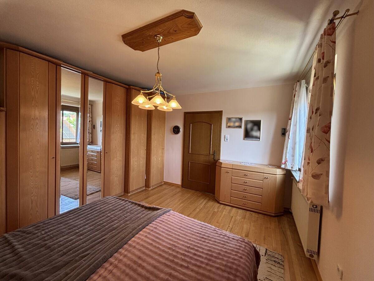 Schlafzimmer mit großem Kleiderschrank, Doppelbett und Holzboden.