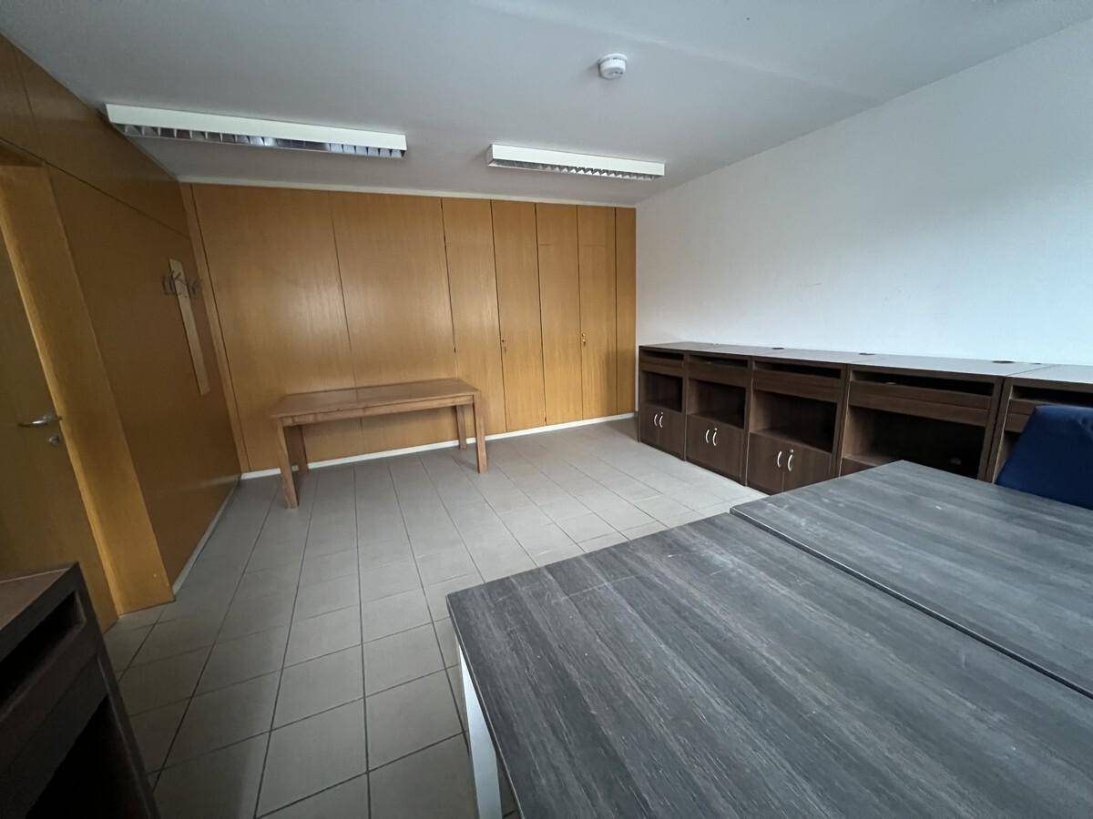 Geräumiges Büro mit Holzvertäfelung, Fliesenboden und mehreren Schreibtischen sowie Regalen.