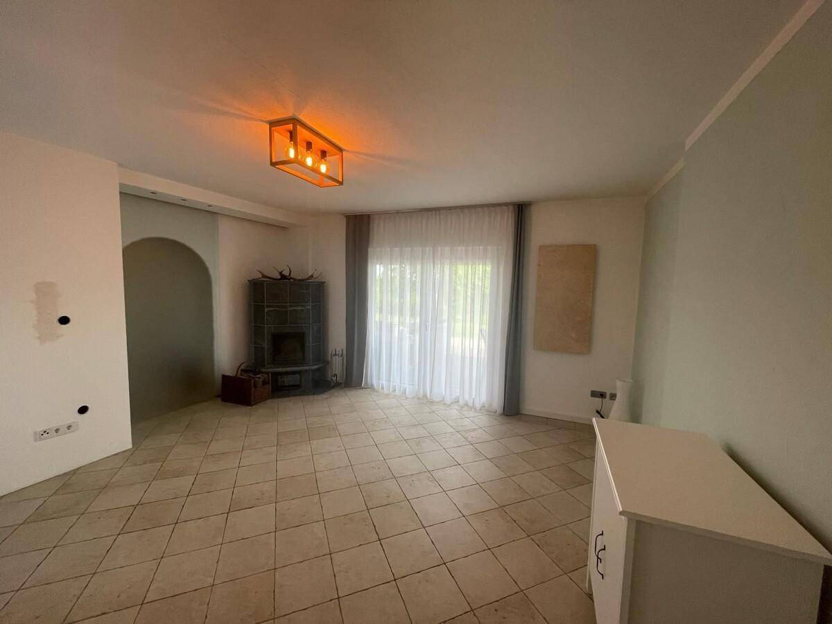 Helles Wohnzimmer mit Fliesenboden und einem modernen Kaminofen für gemütliche Abende.