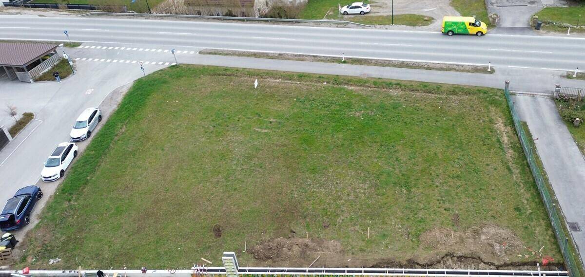 Luftaufnahme eines unbebauten Grundstücks mit angrenzender Straße und parkenden Fahrzeugen.