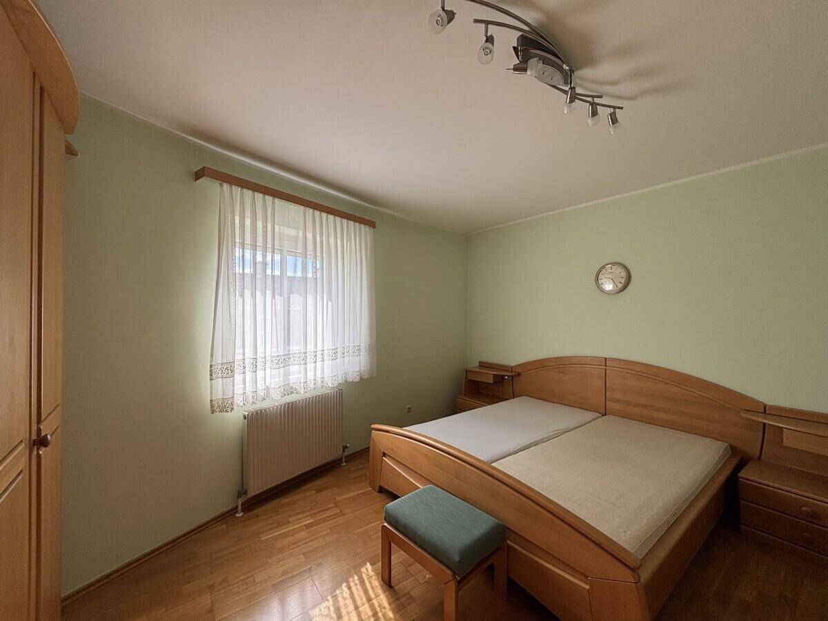 Helles Schlafzimmer mit Parkettboden, Doppelbett und Holzmöbeln.