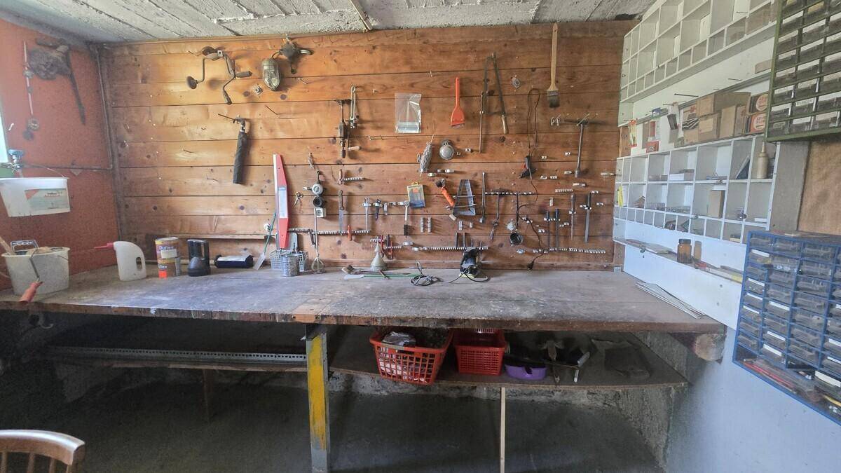 Werkstatt im Keller mit Holzwand, Werkbank und verschiedenen Werkzeugen, gut organisiert.
