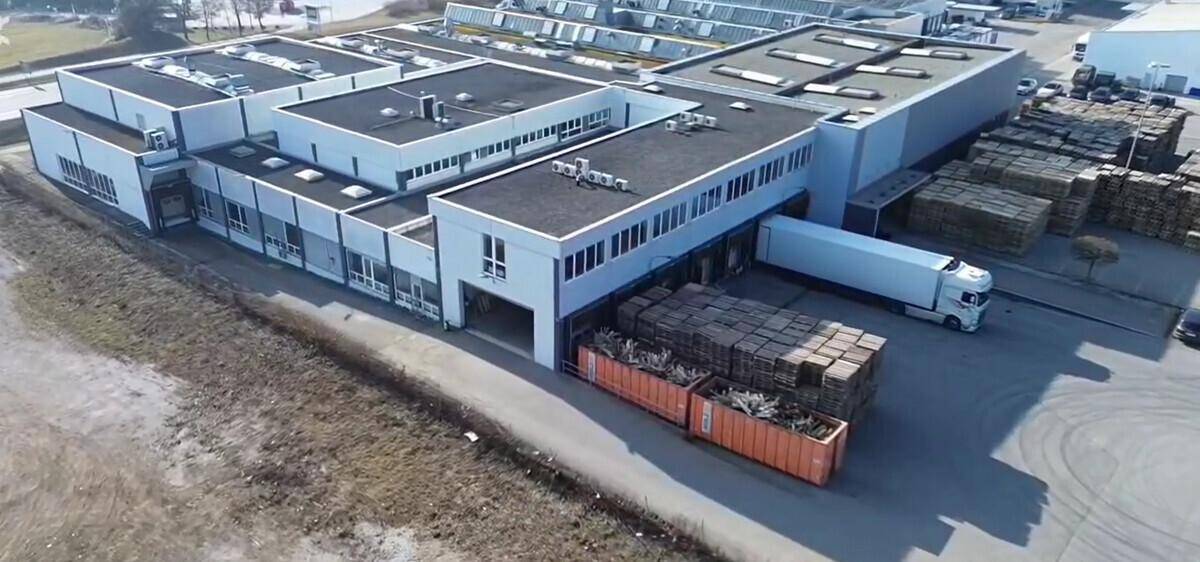 Gewerbegebäude aus der Vogelperspektive mit LKW an der Laderampe und Holzpaletten.